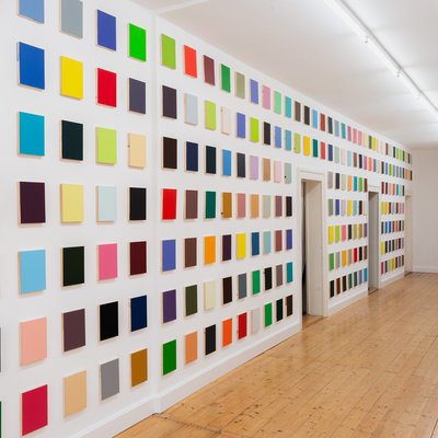 Große Wand voller kleinformatiger Bilder, die alle in einer andere Farbe gemalt sind.